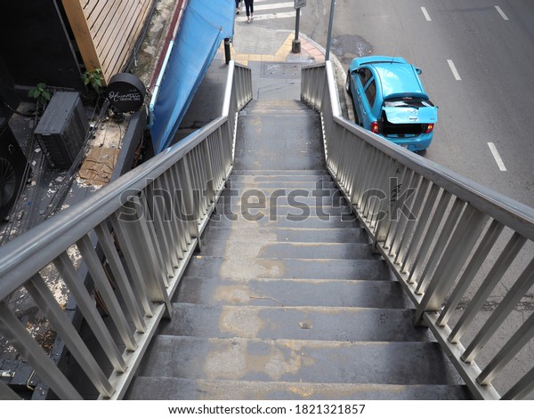 Bangkok, Thailand\
- September 25, 2020: Pedestrians climbing stairs of Crossroad\
footbridge to cross the\
road