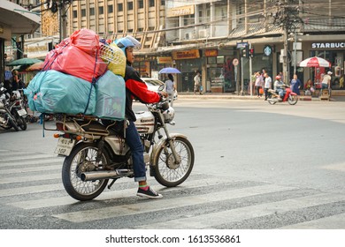 BANGKOK, THAILAND-9 January, 2020: A motorcyclist delivering overloaded stuff to customers on a street near Bangkok’s China town area. The use of motorcycles to transport goods is common in Thailand.