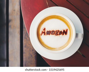 BANGKOK THAILAND-July 7 2019 : Top View Cappuccino Coffee With Text Amazon Brand Name Topping By Coffee Powder In White Ceramic Cup On Wooden Table Background