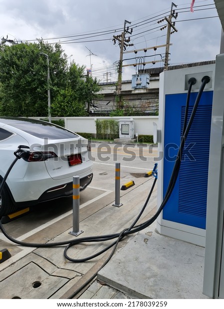 Bangkok,Thailand 10 July 2022:Modern\
electric car (EV Car) plugged in charging on the street station.\
New energy vehicles, eco-friendly alternative energy for\
cars\
\
