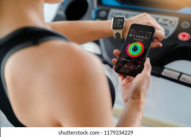 Bangkok,Thailand ,11 Sep 2018 : Close Up Of Apple Watch And IPhone Activity App View Asia Woman Running  Electric Treadmill Work Out Fitness Gym