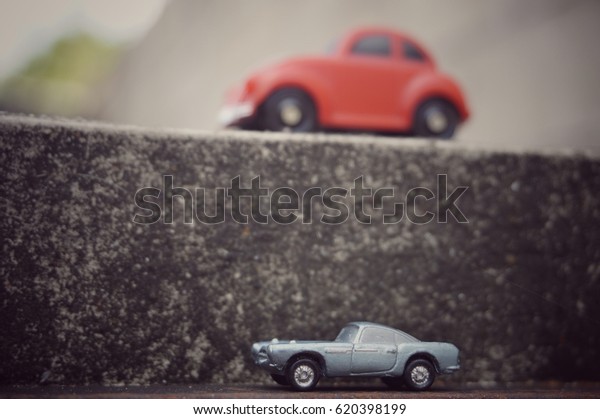 BANGKOK,THAILAND - APRIL13,2017: Focus of vintage blue
toy car on the different heights road with soft focus of wall and
vintage red toy car background.Vintage car model for collection
concept.  