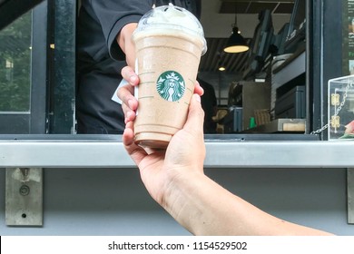 Bangkok,Thailand -August 12, 2018:A service crew serves frappe mocha latte to a customer at drive thru counter.