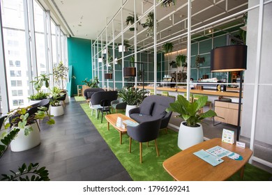 Bangkok,Thailand - August 7, 2020: trendy modern contemporary green and wooden living space decorated with white frame hanging plants and big glass window design where you can see outside view