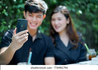 Bangkok,Thailand- December 17,2017 : close up on man hand holding smartphone (iphone X) for take photo (selfie) with girlfriends or video call with family at park, people life style concept
