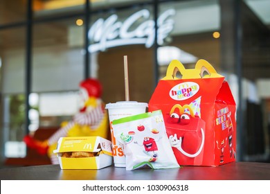 BANGKOK,THAILAND - JANUARY 9,2018 : Happy Meal Set On Desk ,in Soft Focus, With Blurred Ronald Mcdonald At McDonald's Restaurant