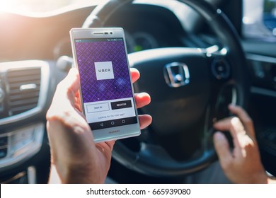 BANGKOK,THAILAND - JUN 24,2016 : Asian Man Holding Uber Driver App Showing On Huewei P7 Smartphone Inside The Car, Hand Of Male Driving Honda Car, Uber Is Smartphone App-based Transportation Network.