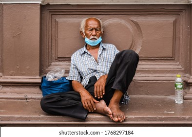 BANGKOK/THAILAND - JUNE 2020: An Old Tired Asian Homeless Man Sit And Sleep Outside Hua Lamphong Railway Station Wear A Protective Mask Due To COVID-19 Coronavirus