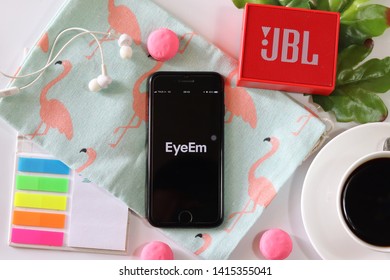 BANGKOK,THAILAND - June 2,2019:Flat Lay Photo With Apple IPhone Opened Eyeem App On The Screen With Coffee Cup ,Loudspeaker ,Earphone ,Tropical Leave  And Macaroon On White Background