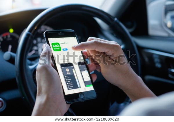 BANGKOK,THAILAND - OCT 30,2018 : Young Asian man\
holding Apple iPhone 6 Plus, download and install Grab Driver app\
from App Store inside the car, Grab is smartphone app-based\
transportation\
network