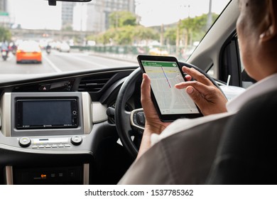 Bangkok/Thailand - October 2, 2019: Asian Grab Taxi Driver Looking Up Direction On A Tablet While Driving
