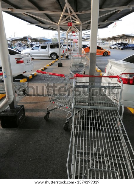 Bangkok,Thailand-17April 2019:Parking\
outside the building of a department store with a large number of\
cars and shopping carts, products parked in a covered\
walkway.