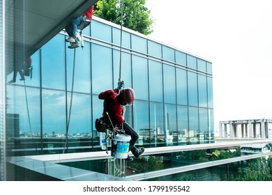 BANGKOK,THAILAND-AUGUST 11 2020:Siriraj Piyamaharun Hospital Building,Maintenance Worker Outside Tall Building Was Abseiling From Upstairs To Ground Floor,Shot Through Glass.