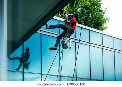 BANGKOK,THAILAND-AUGUST 11 2020:Siriraj Piyamaharun Hospital Building,Maintenance Worker Outside Tall Building Was Abseiling From Upstairs To Ground Floor,Shot Through Glass.