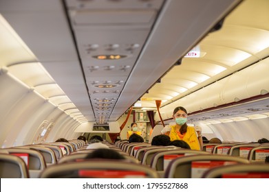 Bangkok,Thailand,August 2020: Female Flight Attendant Of Thai Smile Airway Wearing Face Protect Mask Stands On Aisle To Demonstrate Inflight Safety Instruction With Life Jacket.Travel New Normal