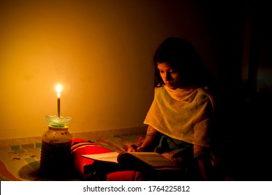 Bangladesh – December 02, 2013: A young girl studying at home with candlelight after electricity load shedding at Dhaka City.