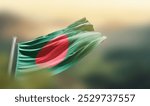 Bangladesh flag waving with beautiful background. The flag blowing with green blur background. Bangladesh national flag for independence day.