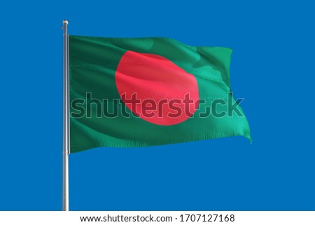 Bangladesh national flag waving in the wind on a deep blue sky. High quality fabric. International relations concept.