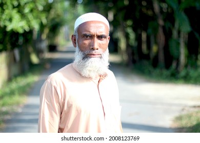 Bangladesh, Rangpur- July 12, 2021. An Old Man Standing On The Street And His Behind The Green Background Blur