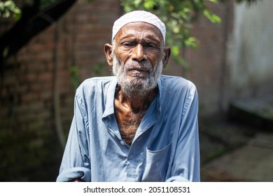 Bangladesh, Rangpur- September 07, 2021. An Old Famine-stricken Old Man Standing In Wearing Dirty Clothes And Behind The Background Blur.