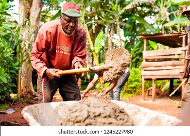 Bangoua, Cameroon - 08 August 2018: Old African Man Doing Manual Work With Shovel And Concrete Building Water Well In Sunndy Day