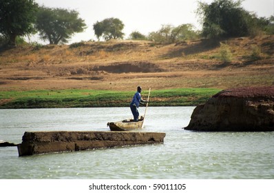 BANI RIVER, MALI - JANUARY 16: Fulani boatman crosses the river at January 16, 2006, Bani River, Mali. There is no bridge on the river, so the only choice is the boat.