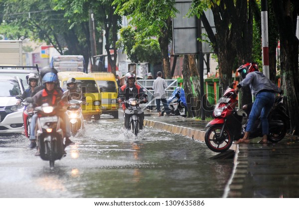 Banjarmasin,\
South Kalimantan, Indonesia, 11 - February 2019: It was raining\
several hours in the flooded city of Banjarmasin, seen by several\
motorbike riders and cars passing the\
flood.