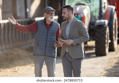 Bank agent and senior farmer talking about business in front of tractor on cattle ranch - Powered by Shutterstock