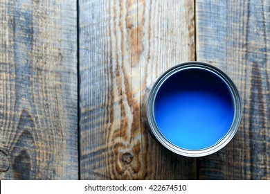 Bank with blue paint standing on wooden boards top view