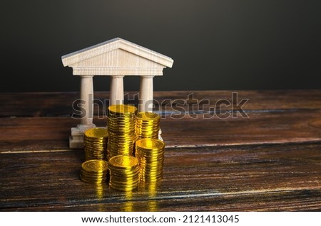 Bank building and coins stacks. State debt. Budget. Tax collection. Investments in education, museums and libraries, government institutions. Bank capitalization. Financial system, commerce and trade.