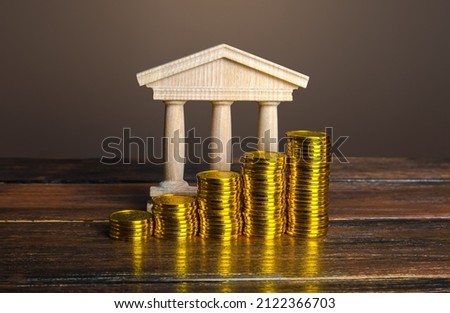 Bank building and increasing stacks of coins. Profitability of deposits and favorable rates for depositors, loyalty programs. Income growth. Increasing taxes collected. Budgeting. Monetary policy.