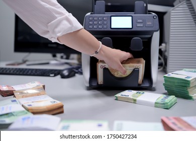 Bank Employees Using Money Counting Machine While Sorting And Counting Paper Banknotes Inside Bank Vault. Large Amounts Of Money In The Bank