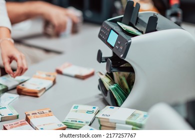 Bank Employees Using Money Counting Machine While Sorting And Counting Paper Banknotes Inside Bank Vault. Large Amounts Of Money In The Bank