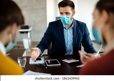 Bank Manager Wearing Face Mask While Communicating With His Clients About Their Financial Reports During A Meeting In The Office.