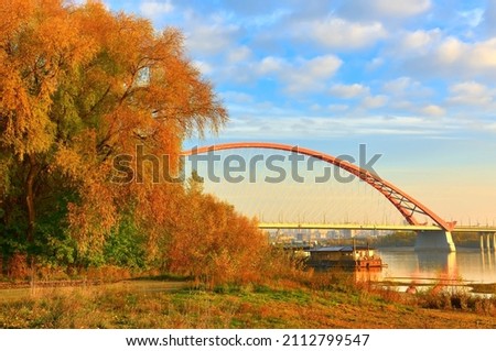 The bank of the Ob River. Arched Bugrinsky bridge on the sandy banks of the river on the outskirts of a large city in golden autumn. Novosibirsk, Siberia, Russia, 2021