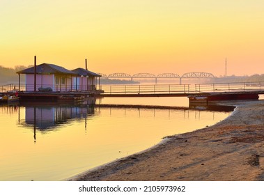 The bank of the Ob River. Sandy beach, boat pier, railway bridge on the horizon in the morning. Novosibirsk, Siberia, Russia, 2021