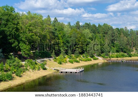 Bank of the Ogre river in the town of Ogre. The embankment is overgrown with forest and a pantone bridge across the river. Countryside and nature of Latvia.