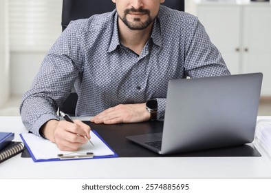 Banker making notes at table in office, closeup