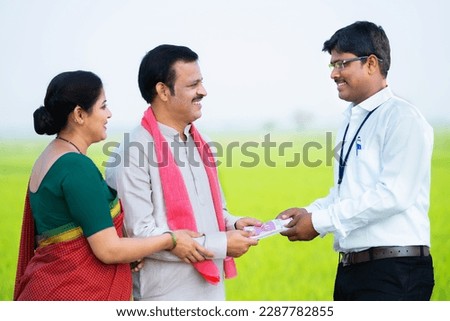 banking Indian officer giving money to farmer village couple at farmland - concept of financial support, investment for agribusiness and loan approval