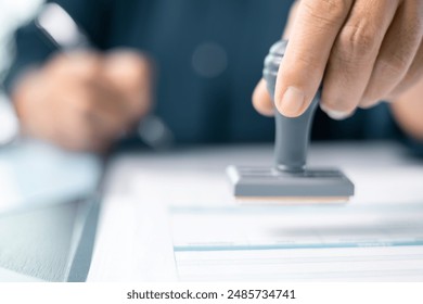 Banking officer stamped the document to approve the loan, finalizing contract and solidifying the finance agreement, fundamental concept in business transactions. approve, loan, stamp, business.