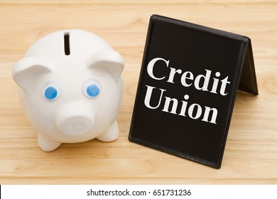 Banking Using A Credit Union, A Piggy Bank On A Desk With Chalkboard With Text Credit Union