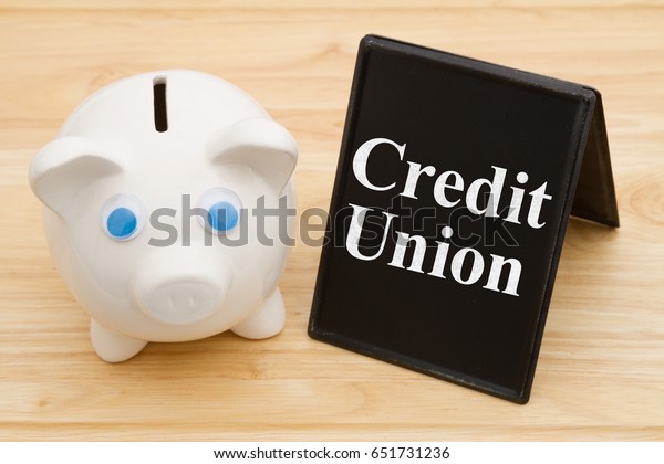 Banking using a credit union, A piggy\
bank on a desk with chalkboard with text Credit\
Union