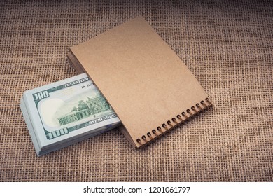 Banknote bundle of US dollar placed on a notebook - Shutterstock ID 1201061797