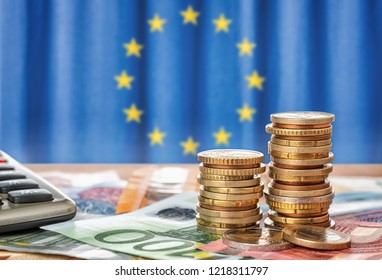 Banknotes And Coins In Front Of The Flag Of The European Union