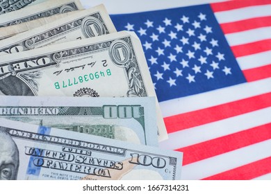 Banknotes Of Different Denominations. Cash On The US Flag. Dollars Next To The Flag. Trading Government Bond Trading. The Concept Is The Value Of Government Bonds. Economy. Buying A Dollar