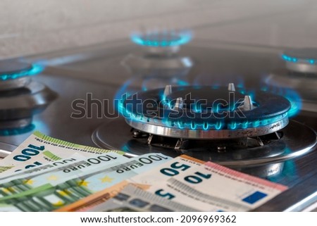 The banknotes lie next to a burning gas burner. The concept is to increase the cost of supply , payment for natural gas. The energy crisis. High cost, price of gas.