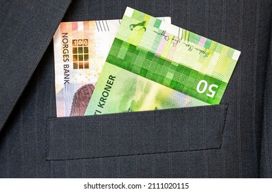 Banknotes of Norwegian krones sticking out of the business suit pocket close up. Money in the pocket of business suit