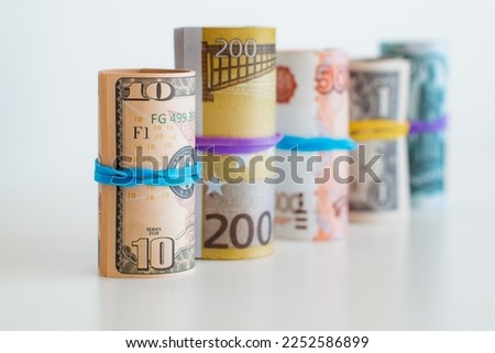 banknotes rolled into a tube stand in a row. Dollar, euro, ruble.