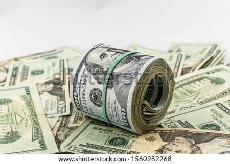 A bankroll of $100 bills on top of a pile of cash