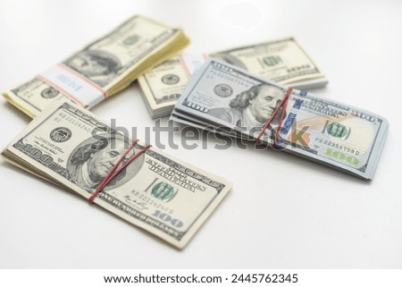 A bankroll of 100 bills on top of a pile of cash